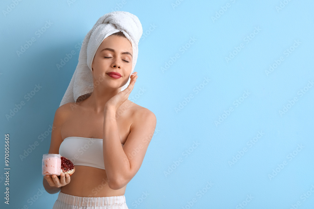 Young woman with pomegranate and jar of cream on blue background Young woman with pomegranate and jar of cream on blue background
