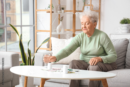 Senior woman with glass of water and pills at home