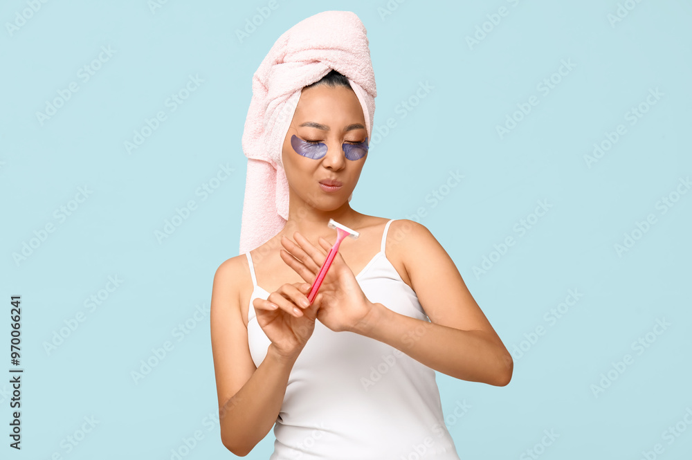 Displeased young Asian woman rejecting razor on blue background Displeased young Asian woman rejecting razor on blue background