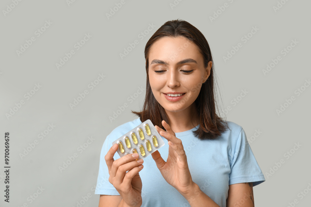 Pretty young woman with pills on grey background Pretty young woman with pills on grey background