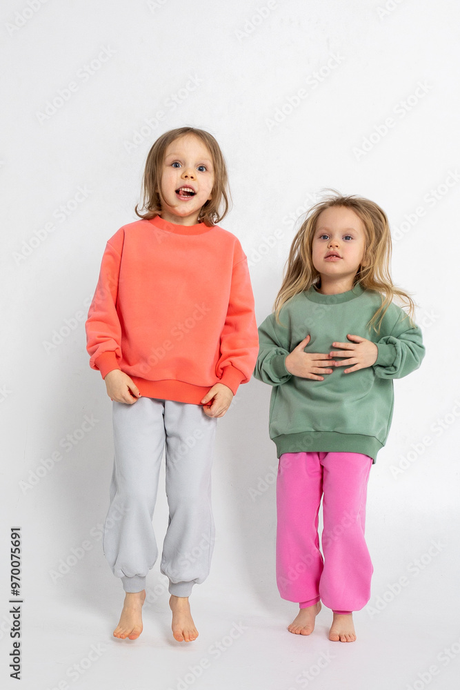Two funny cute girls playing and having fun. Children with smiles and funny emotions on a light background. Vertical photo. High quality photo Two funny cute girls playing and having fun. Children with smiles and funny emotions on a light background. Vertical photo. High quality photo