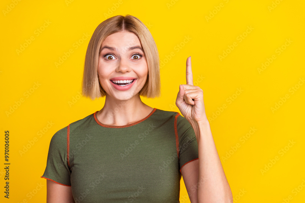 Photo of clever smart girl with bob hairstyle dressed khaki t-shirt raising finger up have idea isolated on yellow color background Photo of clever smart girl with bob hairstyle dressed khaki t-shirt raising finger up have idea isolated on yellow color background