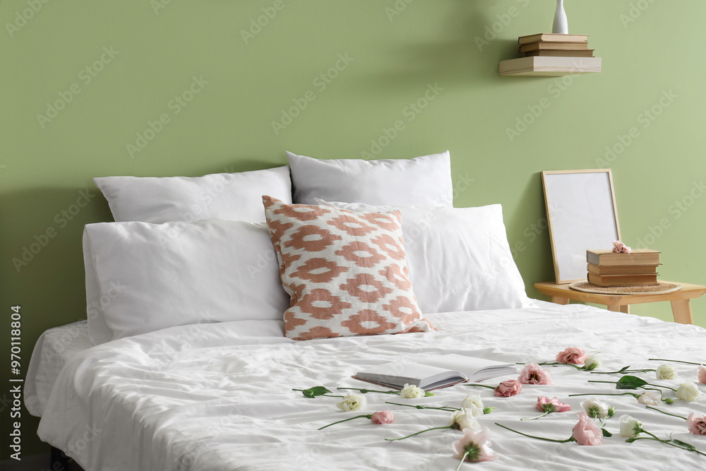 Soft bed with pillows and flowers in stylish bedroom Soft bed with pillows and flowers in stylish bedroom