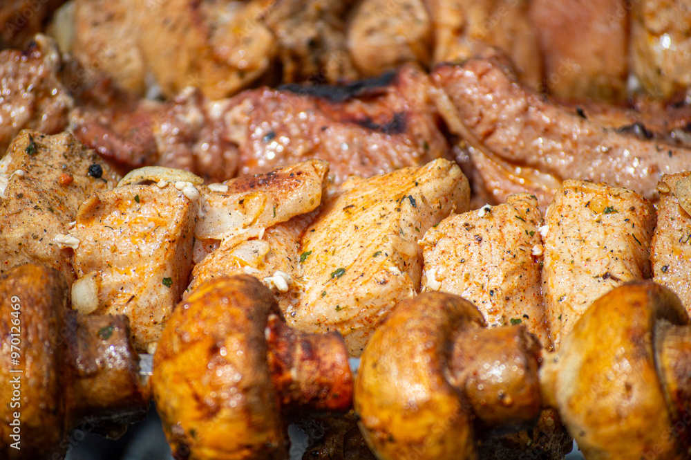 Grilled pieces of pork meat and mushrooms on metal skewers. Shashlik or shish kebab prepared on barbecue grill over hot charcoal with grilled vegetables. Grilled pieces of pork meat and mushrooms on metal skewers. Shashlik or shish kebab prepared on barbecue grill over hot charcoal with grilled vegetables.