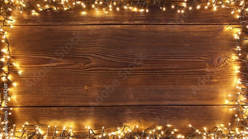 Christmas lights frame loop on rustic wooden background. Realistic garland on old wooden planks. 
 photo