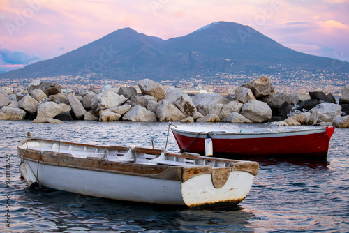 Picturesque view of Mount Vesuvius at sunset, Naples, Italy.  Two traditional boats in the foreground, capturing the essence of Naples's landscape
