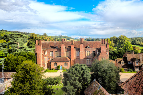 Aerial view of an old manor house, a church and a graveyard in the English countryside.