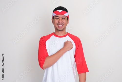 Indonesian man smiling and put fist on his chest photo