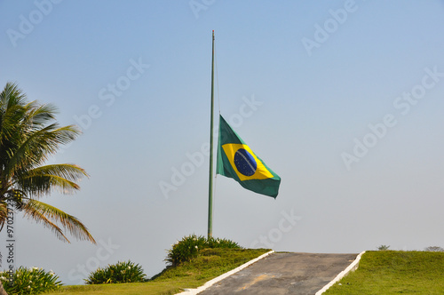 Brazilian flag fluttering in the wind at half-mast in mourning. In the center of the flag with the words “order and progress” in Portuguese. flag day. proclamation of the Republic. proclamation of the