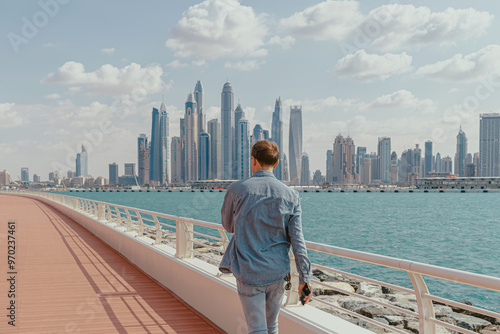 Man walking on a deck along a waterfront with city skyline in the background