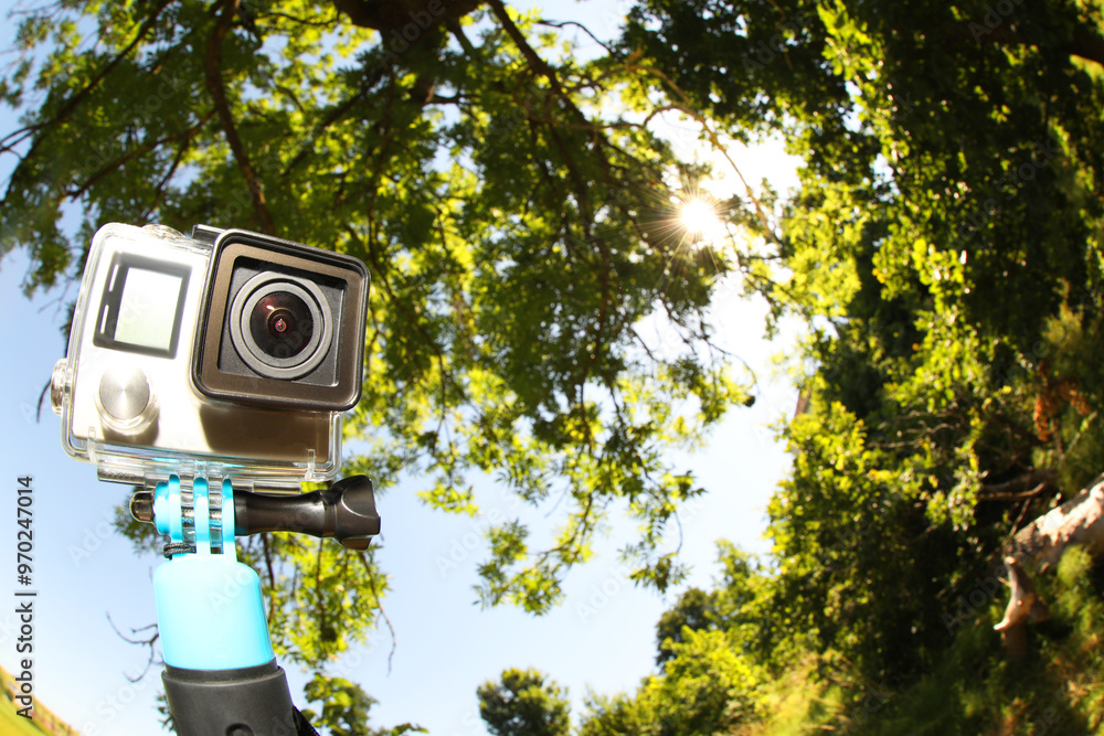 Modern action camera with monopod outdoors, space for text. Fisheye lens effect Modern action camera with monopod outdoors, space for text. Fisheye lens effect