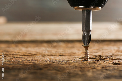 Screwing screw into wooden surface, closeup. Space for text