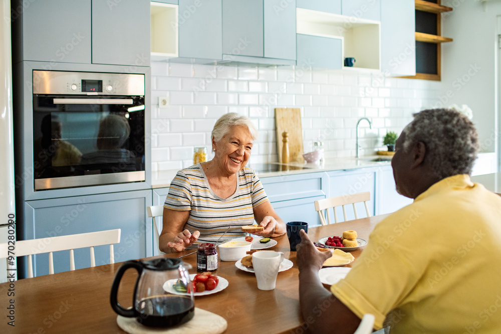 Diverse senior couple eating breakfast together on the kitchen table Diverse senior couple eating breakfast together on the kitchen table