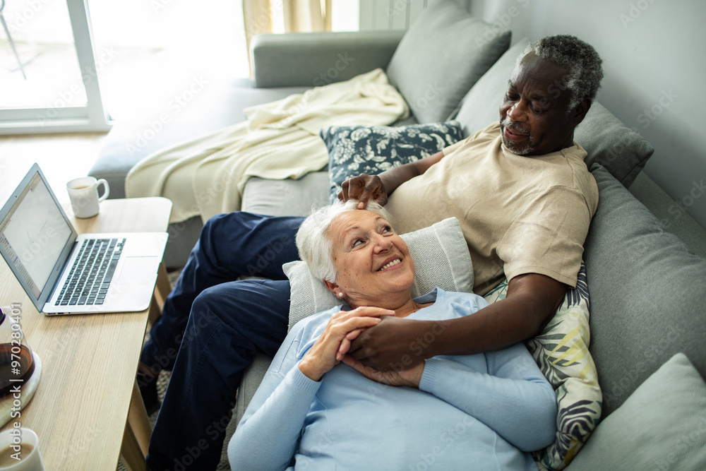 Diverse senior couple relaxing together on the couch at home Diverse senior couple relaxing together on the couch at home