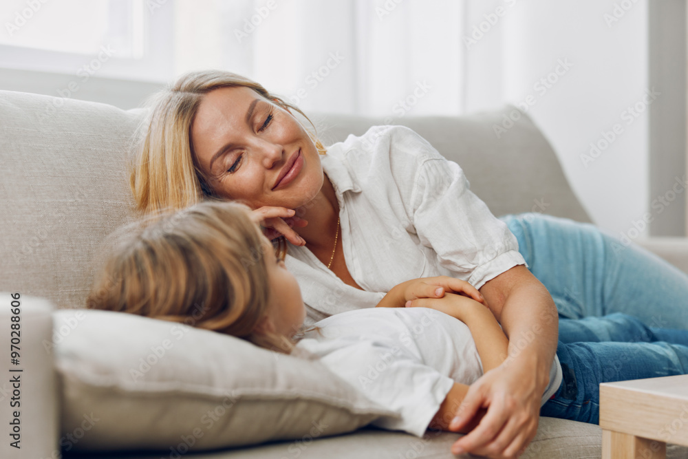 Mother and daughter relaxing on couch with coffee table in cozy living room setting Mother and daughter relaxing on couch with coffee table in cozy living room setting