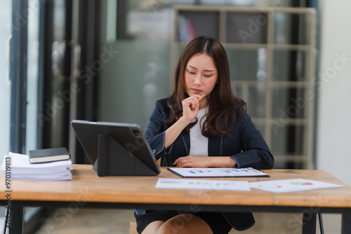 Businesswoman Analyzing Data: A focused businesswoman examines financial reports on her tablet, lost in contemplation at her desk. The image captures the intensity of her thought process, the seriousn