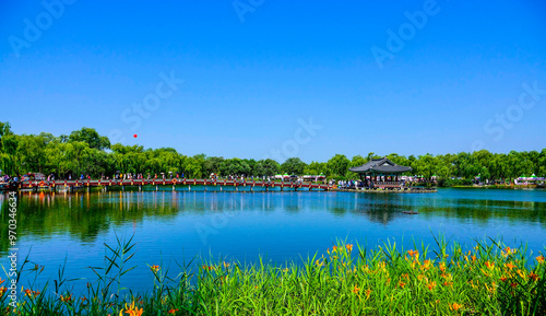 Buyeo-gun, Chungcheongnam-do, South Korea - July 6, 2019: Lilies besides Gungnamji Pond with the background of a pavilion and wooden bridge photo