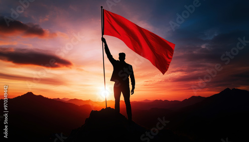 A man is holding a red flag on top of a mountain