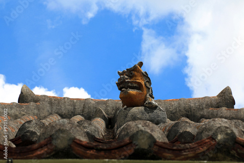 Okinawa, Japan - June 6, 2019: Low angle view of a lion statue on roof tile house at Ryukumura Folk Village photo