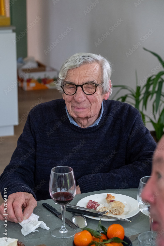 An elderly gentleman enjoys his meal at a table with fine wine, delicious food, and bright citrus fruits An elderly gentleman enjoys his meal at a table with fine wine, delicious food, and bright citrus fruits