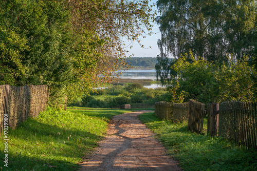 View of the territory of Mikhailovskoye Estate of the Pushkin Museum-Reserve and Lake Kuchane in the background on a sunny summer day, Pushkinskiye Gory, Pskov region, Russia