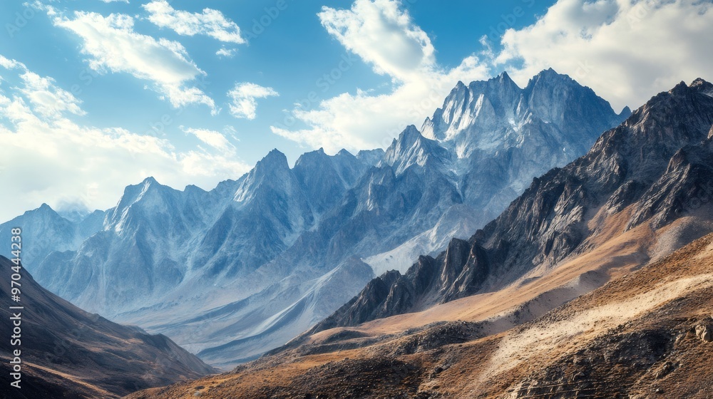 Majestic mountain range with snow-capped peaks under a bright blue sky with fluffy clouds. Majestic mountain range with snow-capped peaks under a bright blue sky with fluffy clouds.