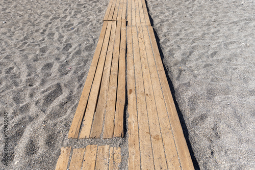 Empty wooden walkways lie on the beach sand on a sunny summer day photo