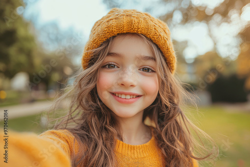 Adorable girl in a trendy outfit taking a selfie for a live stream blog outdoors