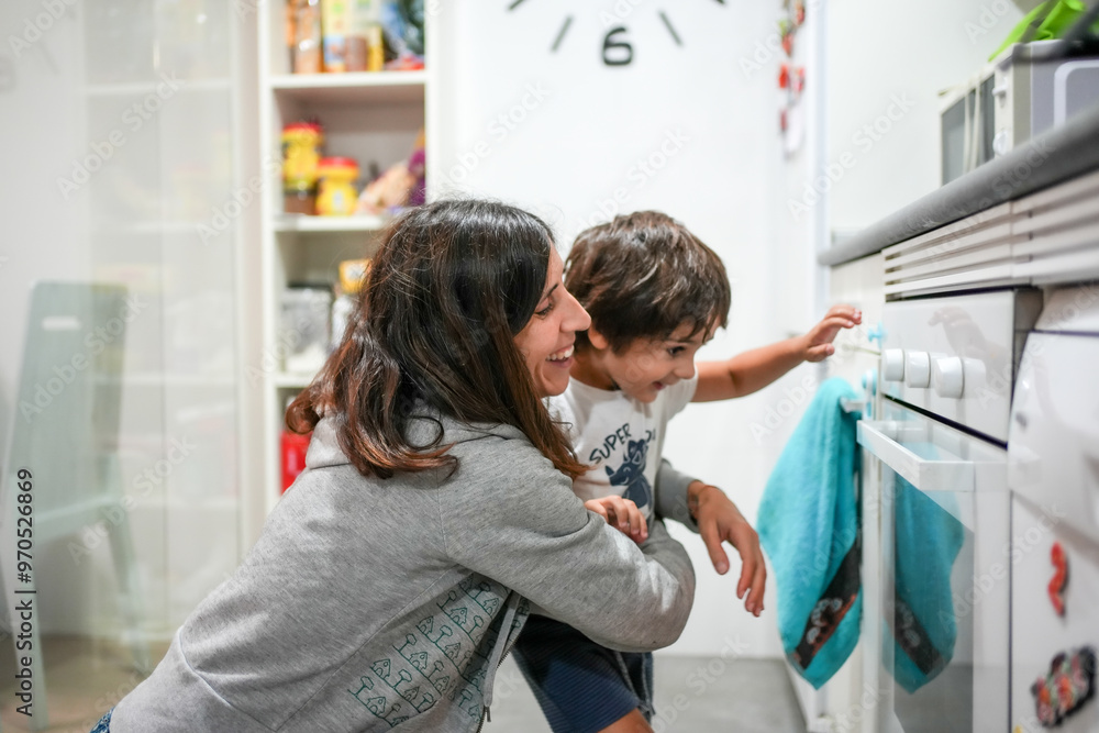 A woman and a child are in a kitchen, with the woman smiling at the child A woman and a child are in a kitchen, with the woman smiling at the child