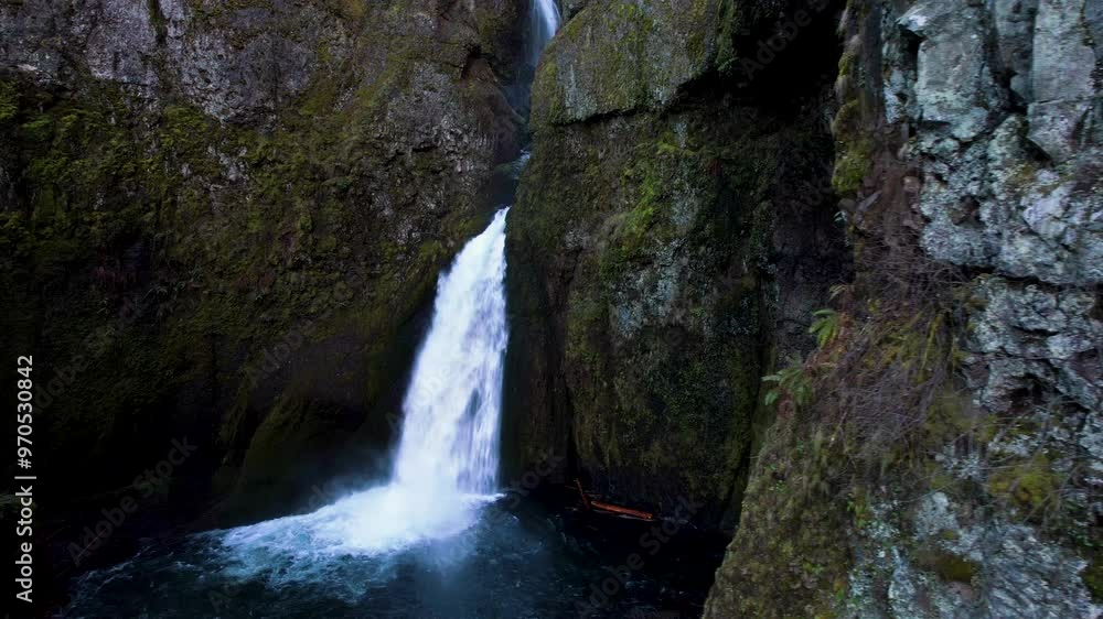 A drone moving around a cliffside to reveal a water fall. A drone moving around a cliffside to reveal a water fall.