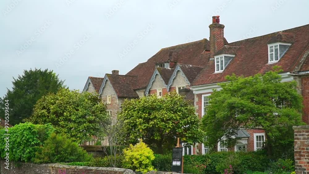 A picturesque view of a traditional English house with a red-tiled roof, surrounded by lush greenery and a well-maintained garden. A picturesque view of a traditional English house with a red-tiled roof, surrounded by lush greenery and a well-maintained garden.