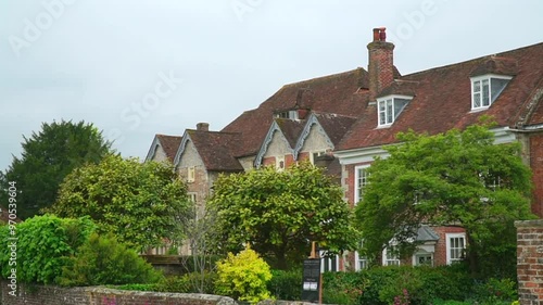 Wallpaper Mural A picturesque view of a traditional English house with a red-tiled roof, surrounded by lush greenery and a well-maintained garden. Torontodigital.ca