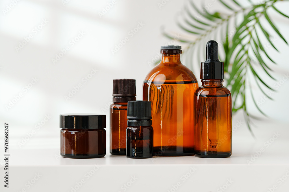 Collection of Amber Glass Bottles and Jars for Essential Oils on a White Surface Collection of Amber Glass Bottles and Jars for Essential Oils on a White Surface