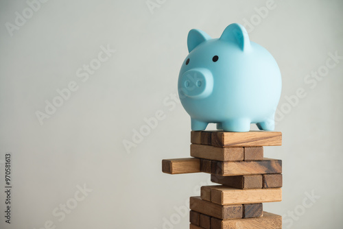 Quadro em tela Blue piggy bank on unstable wood tower block game with white wall background copy space