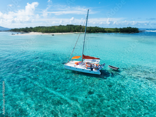 Aerial views of a catamaran in clear blue and greenish water off the coast of a tropical island. Grand Baie, Mauritius