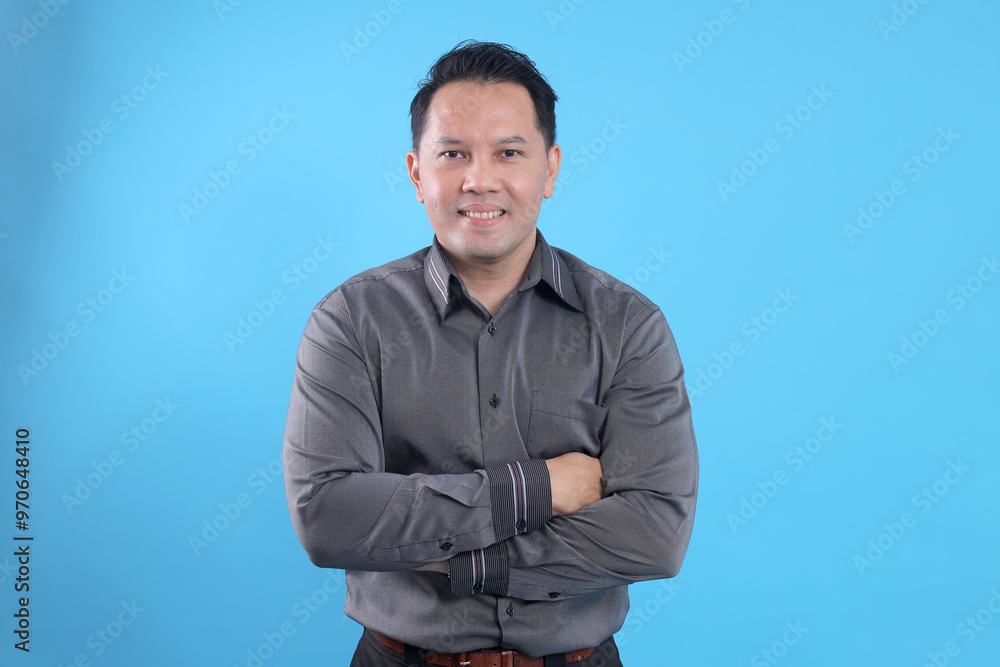 Portrait of confident Asian businessman posing with crossed arms isolated on blue background Portrait of confident Asian businessman posing with crossed arms isolated on blue background