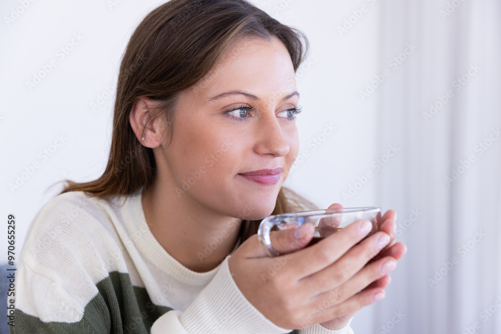 At home, Holding glass cup, woman enjoying relaxing moment in cozy home setting At home, Holding glass cup, woman enjoying relaxing moment in cozy home setting