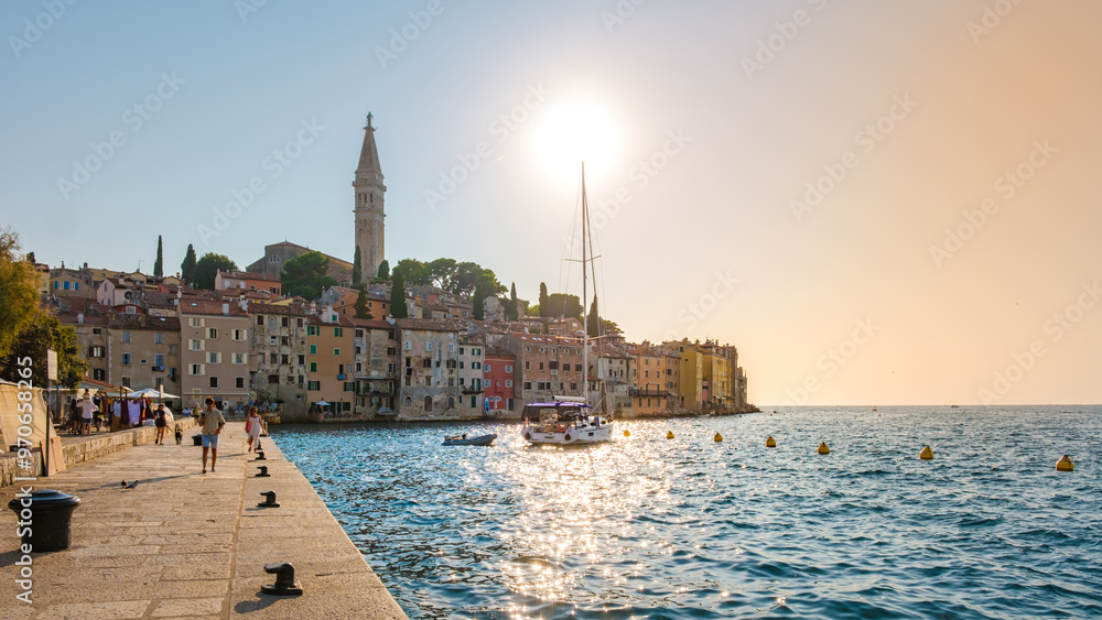 As the sun sets over Rovinj, its golden rays enhance the vibrant, colorful buildings along the waterfront. A sailboat gently rocks on the serene waters, inviting evening tranquility. As the sun sets over Rovinj, its golden rays enhance the vibrant, colorful buildings along the waterfront. A sailboat gently rocks on the serene waters, inviting evening tranquility.