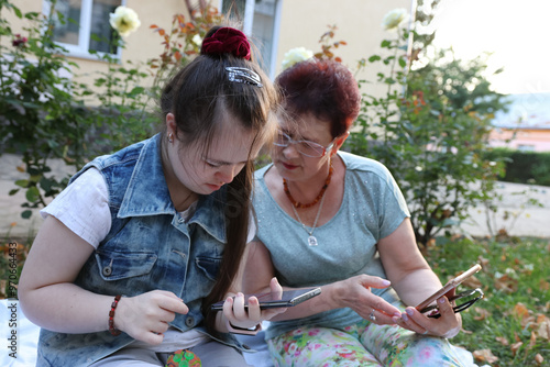Obraz na plátne Mother and daughter with Down syndrome walking and using smartphone