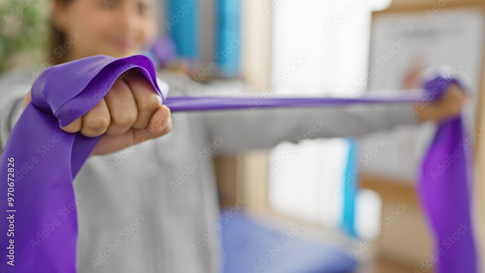 A focused young woman exercises with resistance bands in a bright physiotherapy clinic, embodying health and rehabilitation. A focused young woman exercises with resistance bands in a bright physiotherapy clinic, embodying health and rehabilitation.