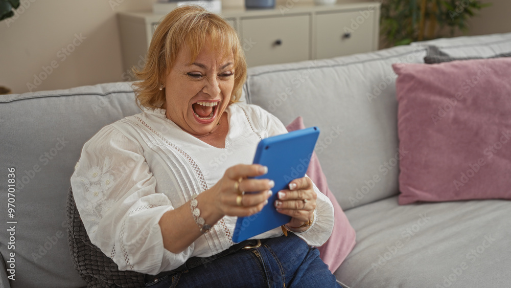An elderly caucasian woman laughing joyfully while using a blue tablet, sitting comfortably in her living room at home. An elderly caucasian woman laughing joyfully while using a blue tablet, sitting comfortably in her living room at home.