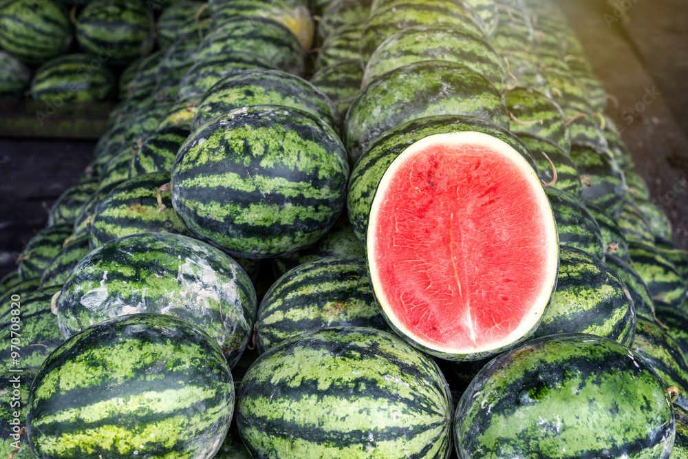Φωτογραφία Pile stacked in a pyramid shape of watermelons on a stall for sell at watermelon wholesale store there is a cut in half to show the fresh and juicy ripe red color at fruit market of Thailand