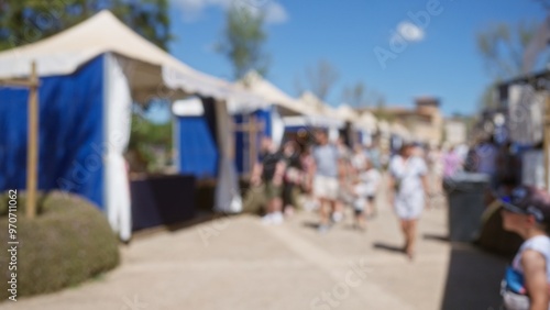 Blurred crowd enjoying outdoor market in sunny mallorca with people browsing various stalls with blue tents in the background creating a relaxed and lively atmosphere