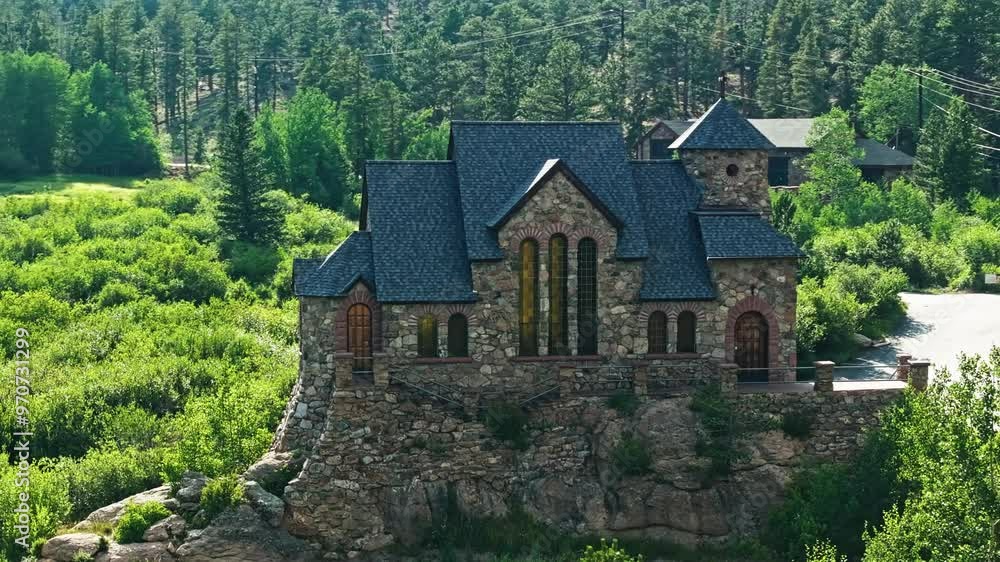 Sunlight and greenery glow through amber colored stain glass of chapel in the forested mountains at midday Sunlight and greenery glow through amber colored stain glass of chapel in the forested mountains at midday