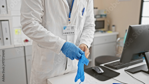 Foto A male healthcare professional dons blue gloves in a laboratory setting, preparing for a medical procedure