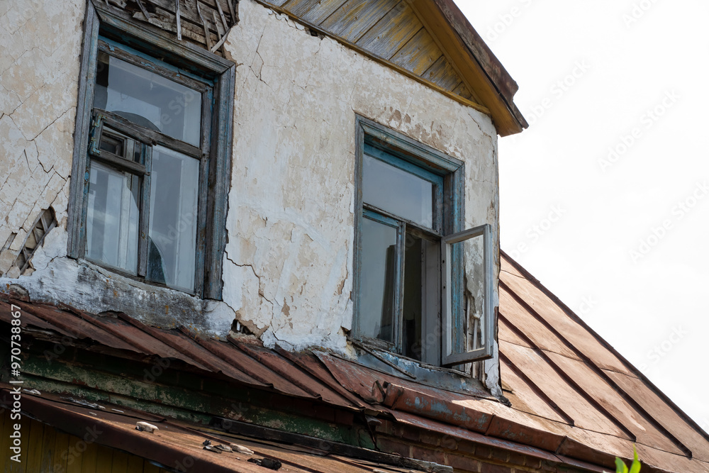 An aged building characterized by a rusty roof and shattered windows An aged building characterized by a rusty roof and shattered windows