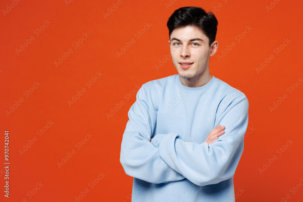Young smiling happy confident Caucasian man wears blue sweatshirt casual clothes hold hands crossed folded look camera isolated on plain red orange color background studio portrait. Lifestyle concept. Young smiling happy confident Caucasian man wears blue sweatshirt casual clothes hold hands crossed folded look camera isolated on plain red orange color background studio portrait. Lifestyle concept.