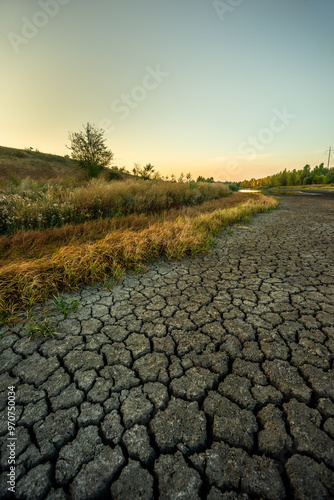 Dry lake at the summer morning , lake near the forest with grass, beautiful landscape with lake . Dry ground , natural effect , global warming in Ukraine . Sunrise over the lake 