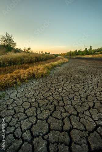 Dry lake at the summer morning , lake near the forest with grass, beautiful landscape with lake . Dry ground , natural effect , global warming in Ukraine . Sunrise over the lake 