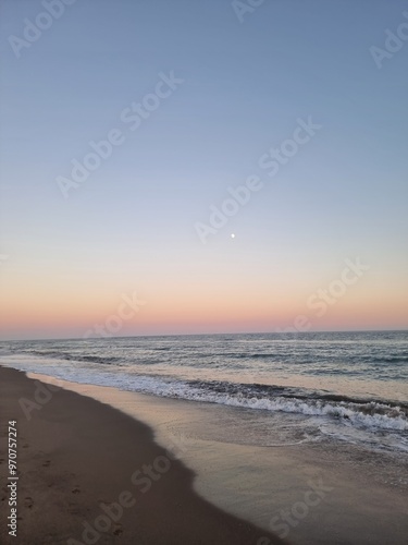 Wallpaper Mural A serene beach scene in Marbella, Spain, captured at twilight with the moon rising over the horizon, and the soft colors of a Mediterranean sunset reflecting on the calm ocean waters. Torontodigital.ca
